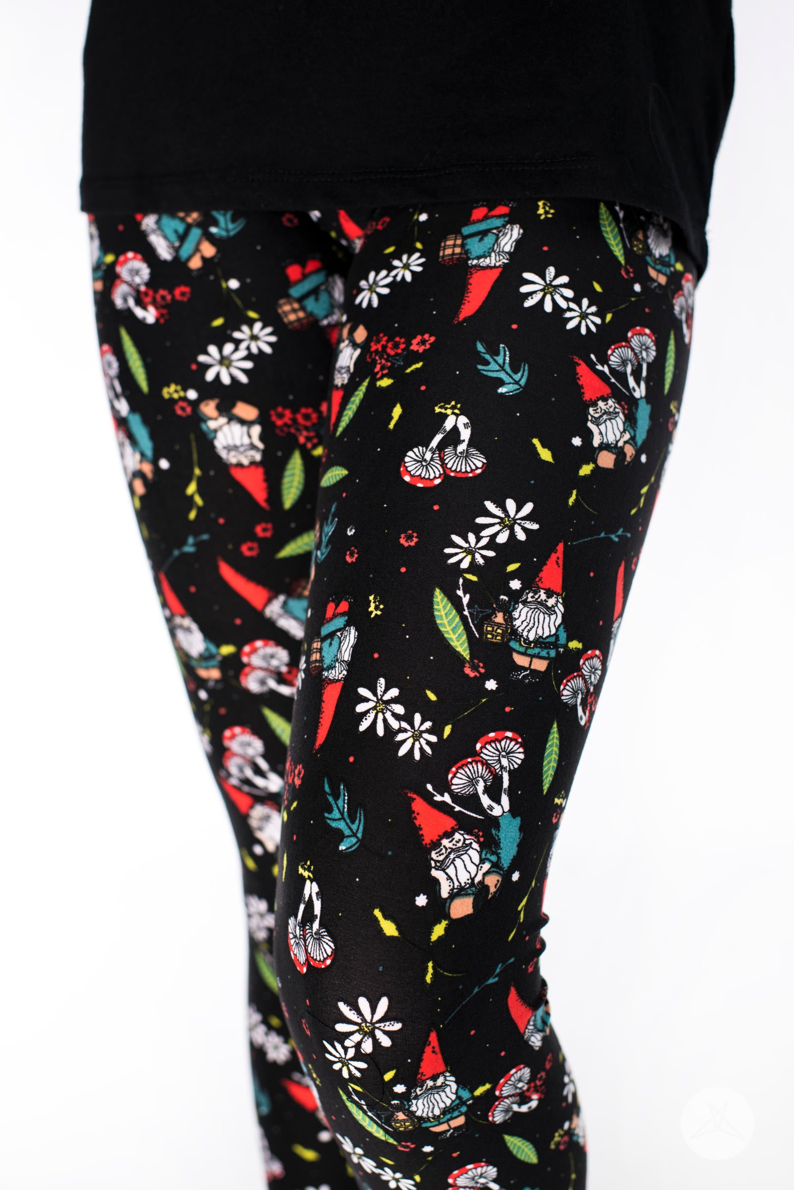 Garden Party Kids leggings by SweetLegs with playful garden gnomes, mushrooms, daisies, and greenery on black background