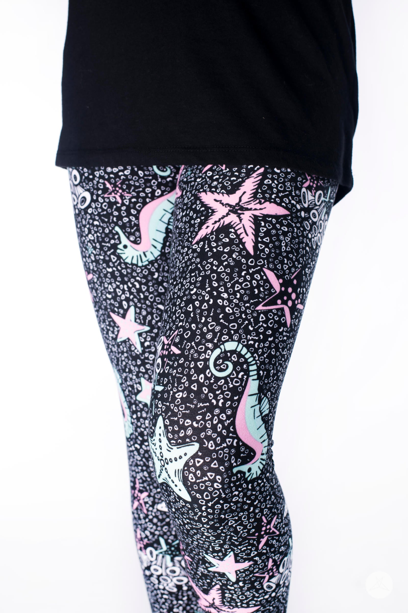 Close-up of SweetLegs Under The Sea Kids leggings with mint and pink sea creatures on black background