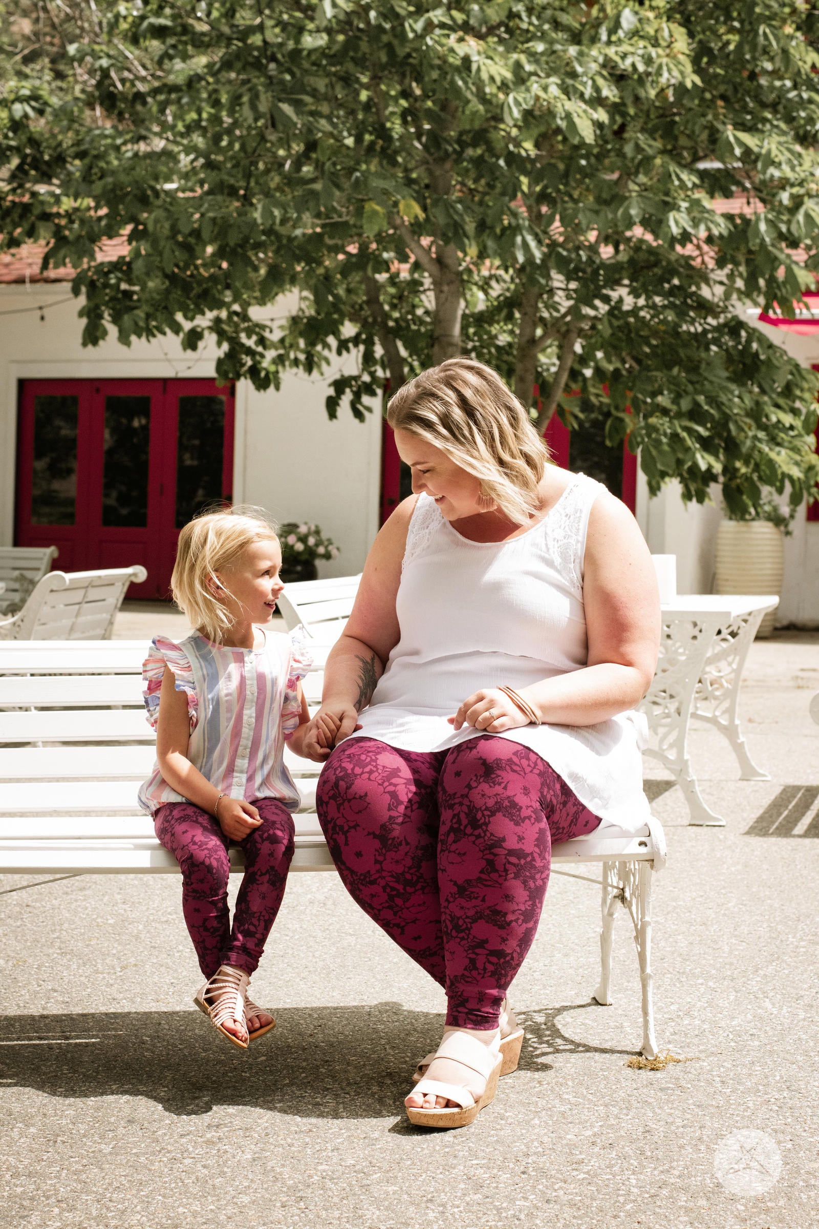 Child sitting on a bench wearing SweetLegs Summer Blush Kids leggings in two-toned merlot and cherry floral print