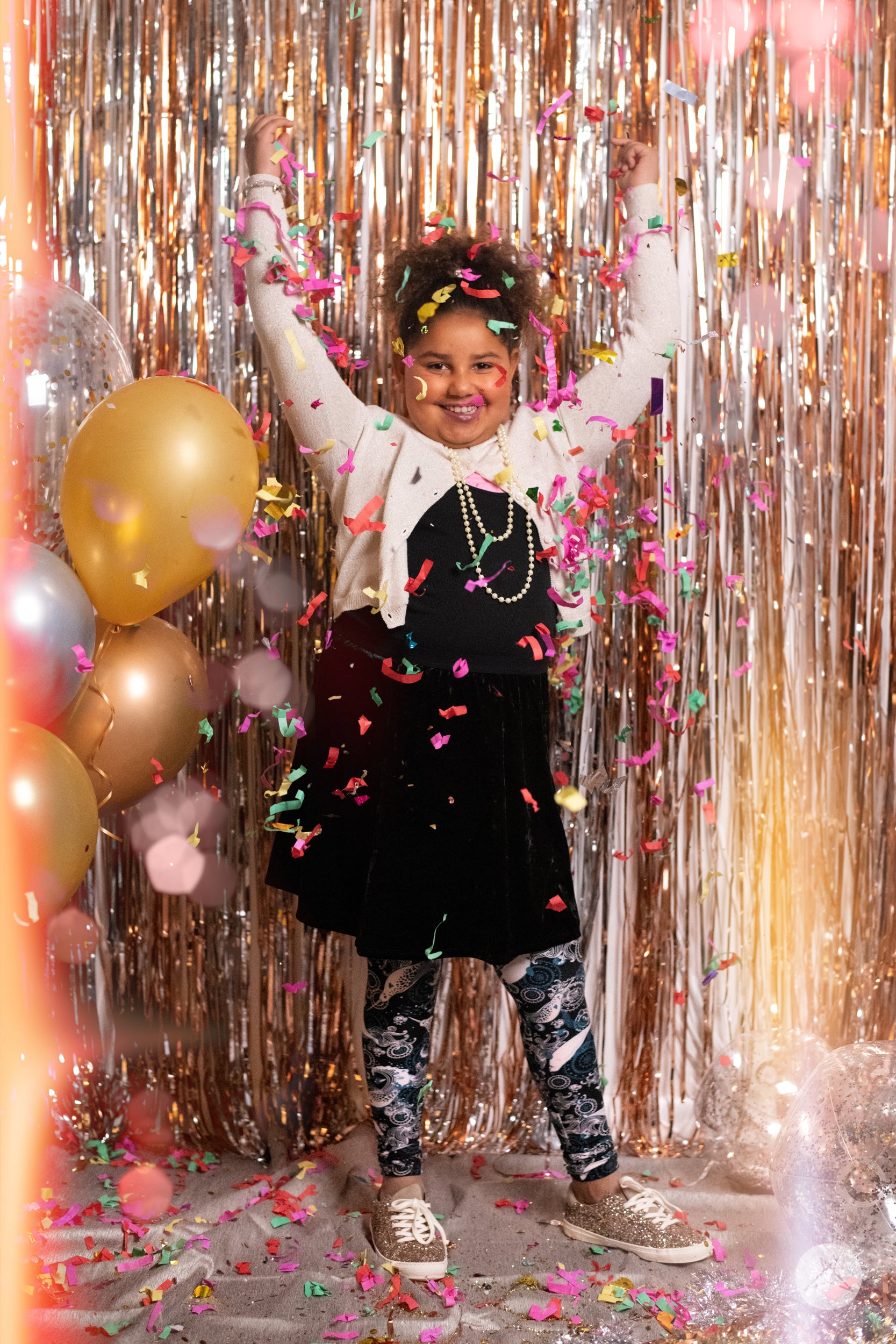 Child celebrating wearing SweetLegs Deep Blue Kids leggings with teal and white narwhal print on black background