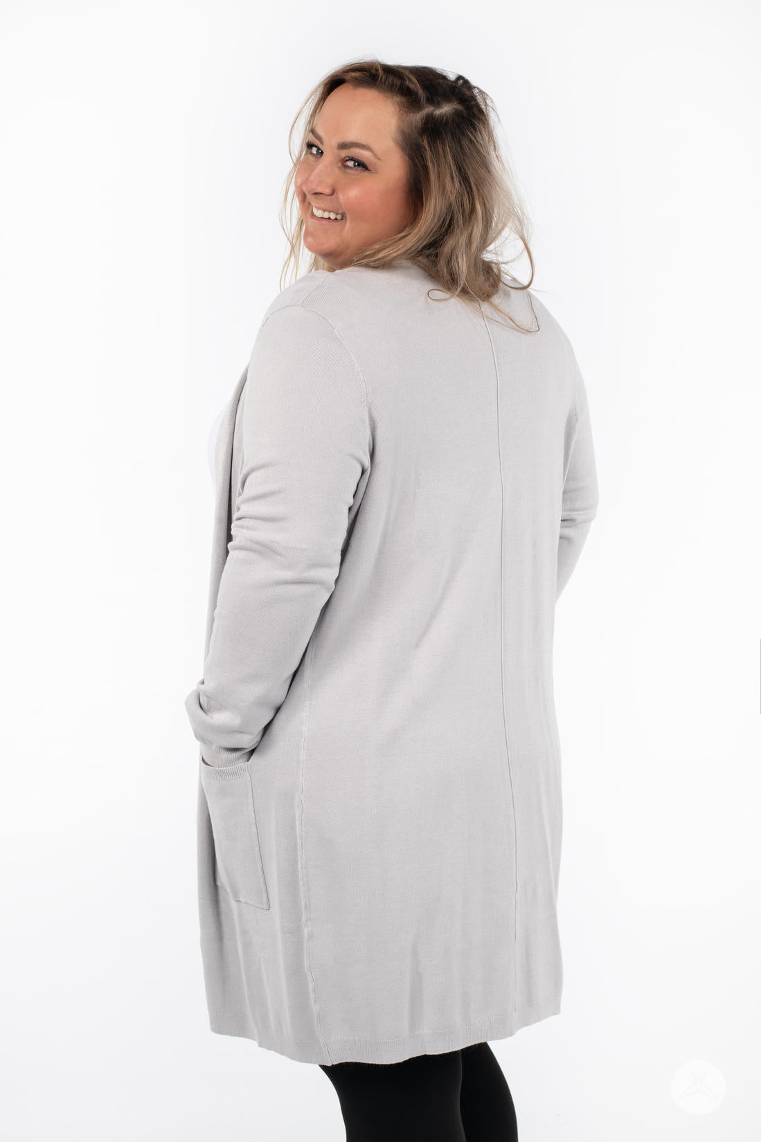 Plus-size model smiling wearing SweetLegs Canada Spring Cardigan in light grey with patch pockets, back view