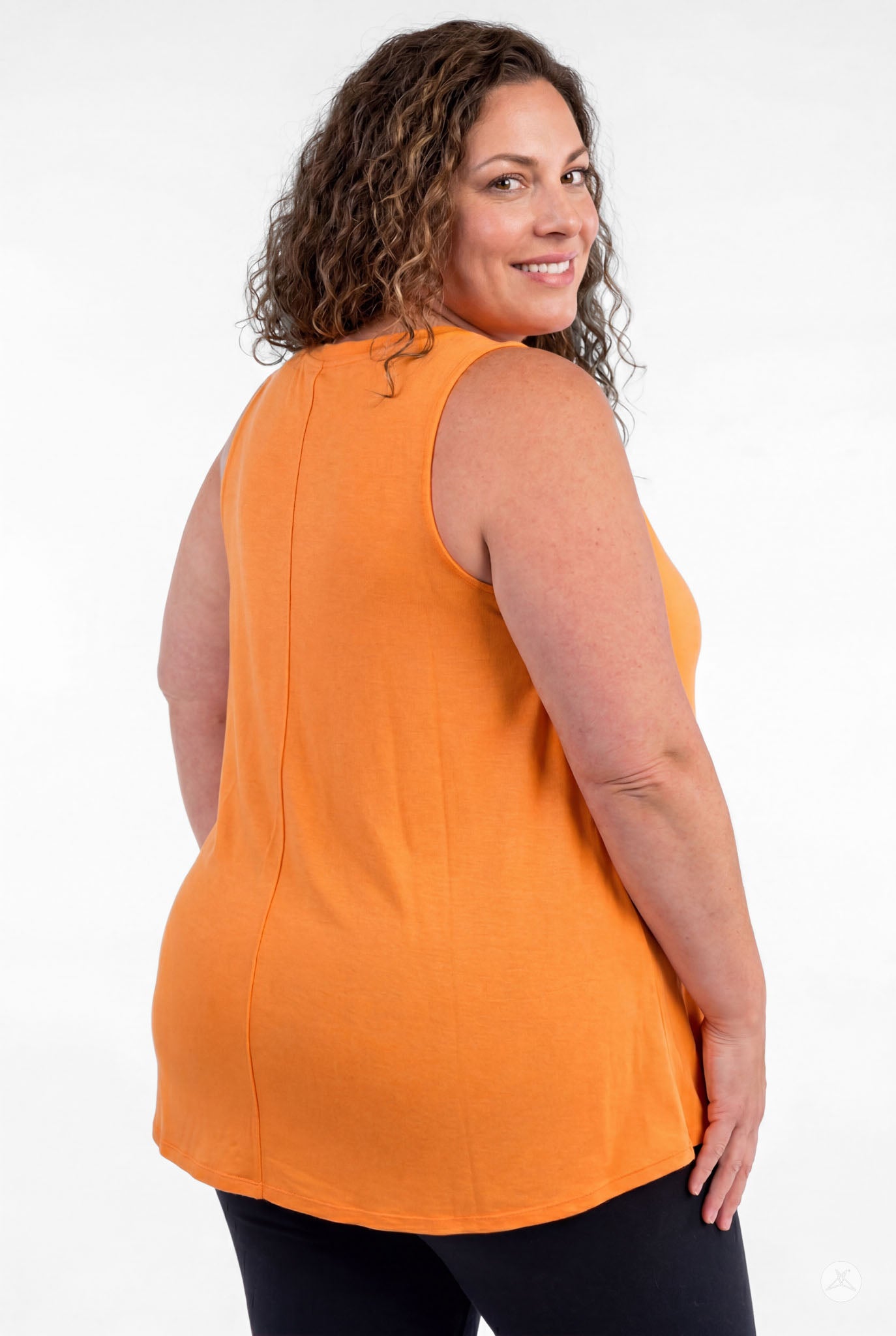 Plus size woman smiling over shoulder wearing sweettops High Neck Tank in vibrant orange and black pants