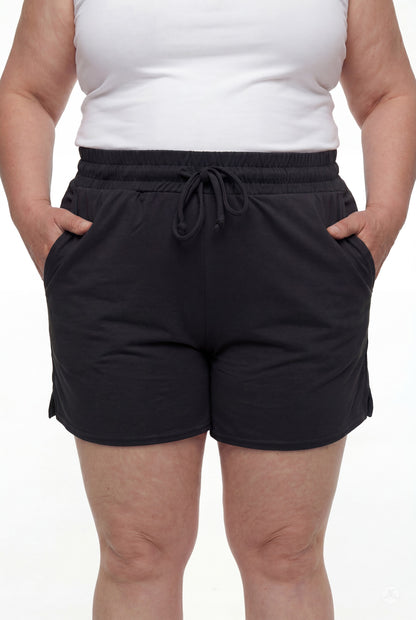Close-up of person wearing black Lounge Shorts by SweetLegs with elastic waistband and drawstring, hands in pockets