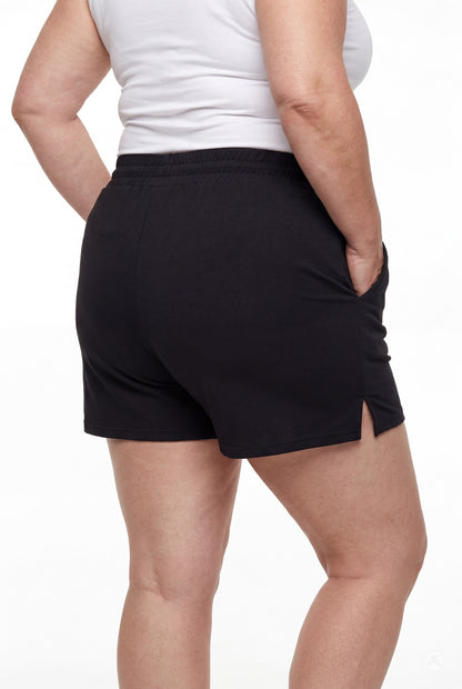 Rear view of person wearing black Lounge Shorts by SweetLegs with side slits and elastic waistband with hands in pockets