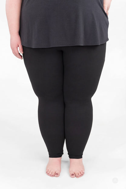 Plus size woman wearing sweetlegs Black Pocket Leggings standing barefoot against a white background