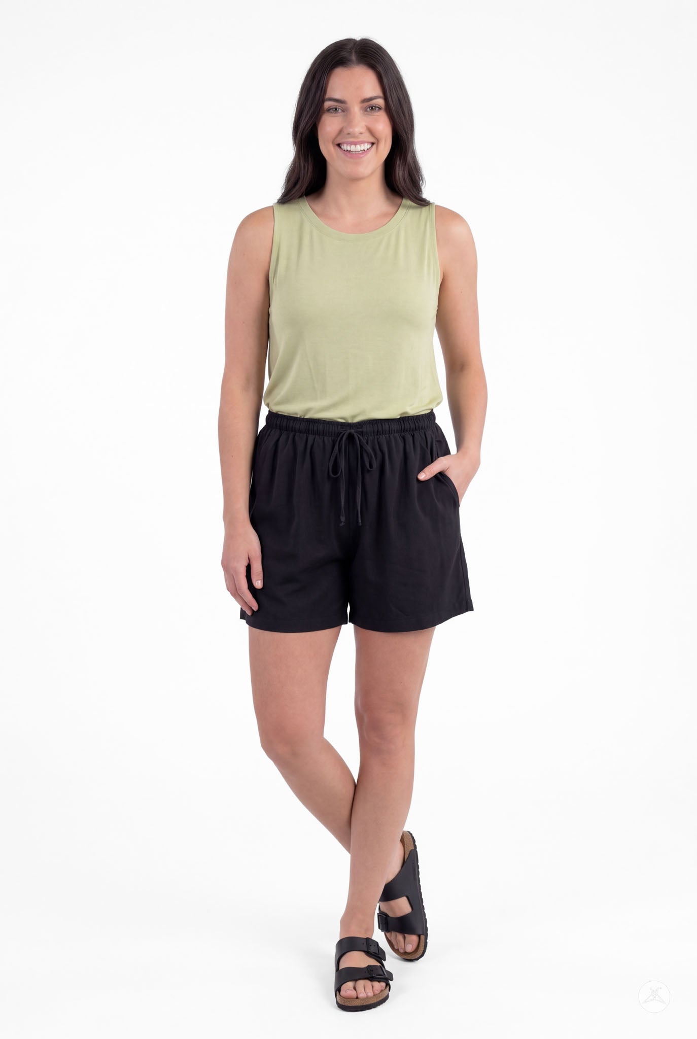Woman wearing SweetLegs Breeze Shorts in black with pockets and drawstring paired with a light green sleeveless top smiling