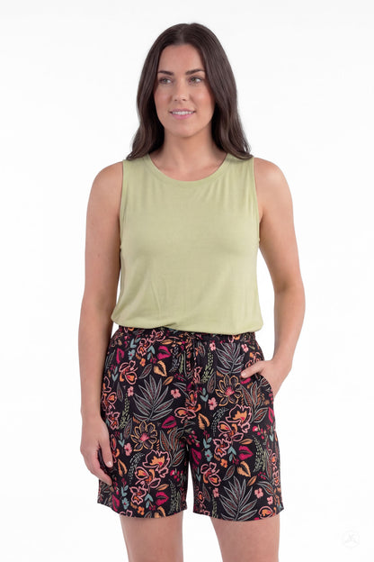 Woman wearing SweetLegs Breeze Shorts with black floral pattern and light green sleeveless top, hand in pocket, standing