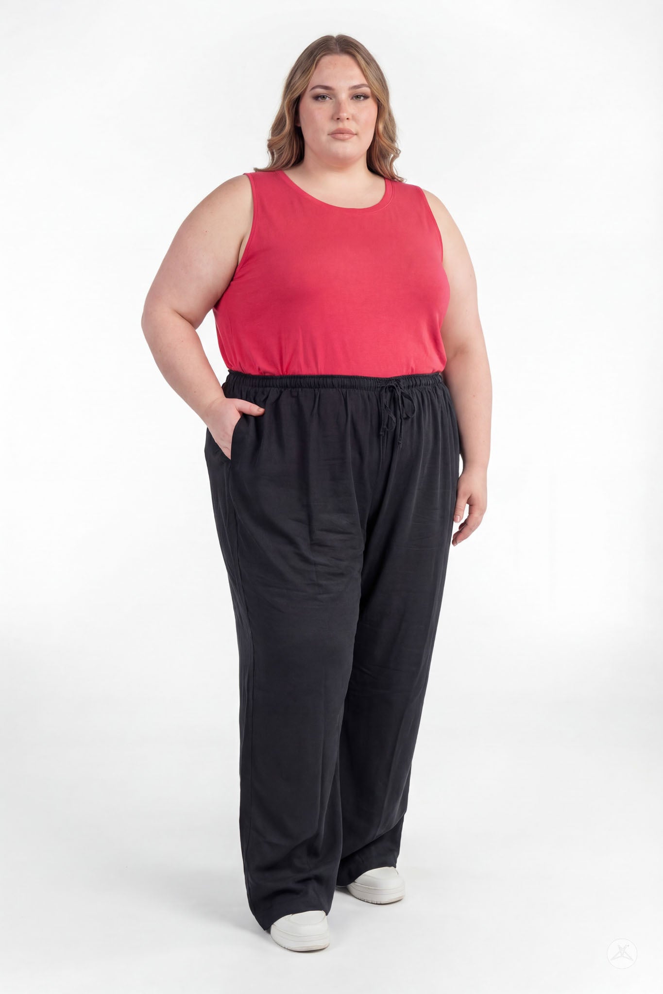 Plus size woman with hands in pockets wearing black Breeze Wide-Leg Pant by sweetlegs and red sleeveless top standing confidently