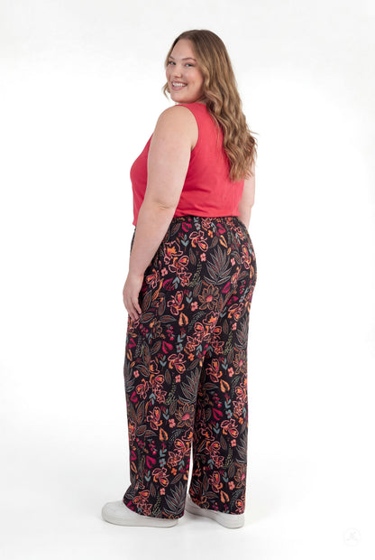 Plus size model smiling wearing sweetlegs Breeze Wide-Leg Pant with vibrant floral print shown from back