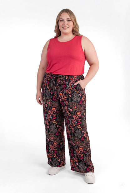 Plus size woman smiling wearing sweetlegs Breeze Wide-Leg Pant with colorful floral print and sleeveless red top