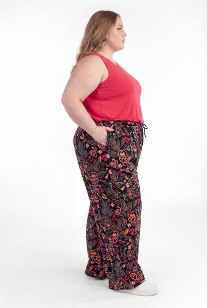 Plus size woman wearing sweetlegs Breeze Wide-Leg Pant with floral print paired with sleeveless red top on white background