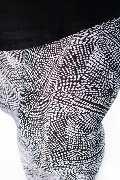 Close-up of SweetLegs Charmed leggings showing black and white abstract dotted snakeskin design on model legs