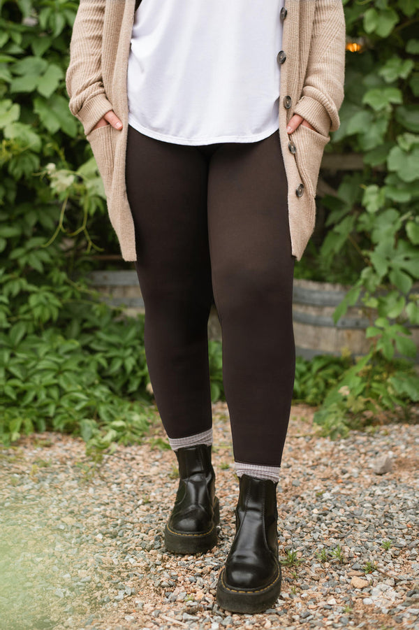Front view of SweetLegs Espresso leggings in rich brown worn with a white top and beige cardigan outdoors