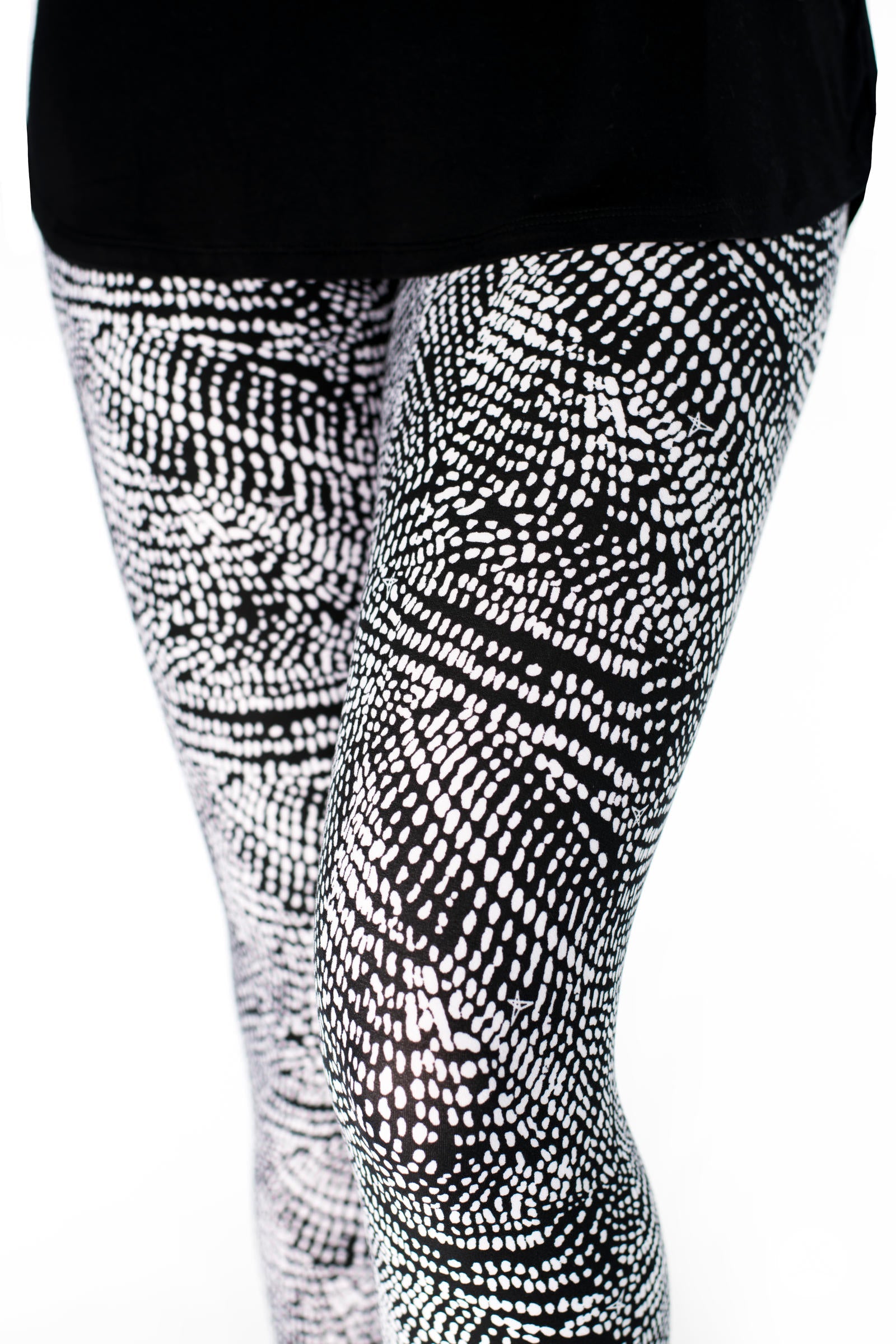 Close-up of SweetLegs Charmed leggings with black and white abstract dots forming a deconstructed snakeskin pattern on legs