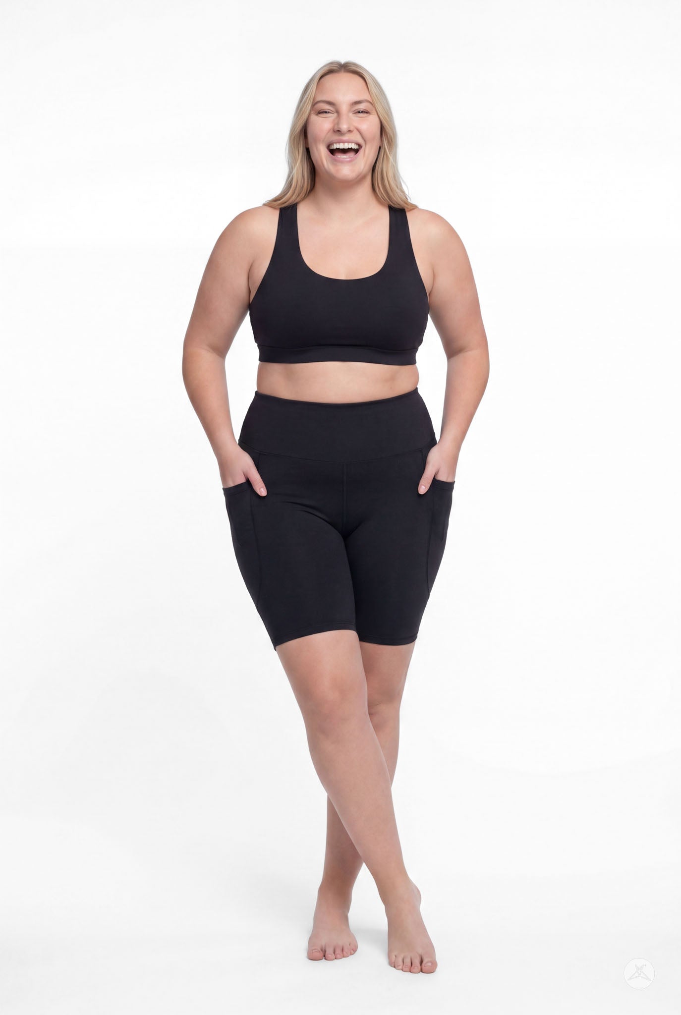 Plus size model smiling wearing SweetLegs Black High-Waisted Pocket Biker Shorts with hands in pockets front view