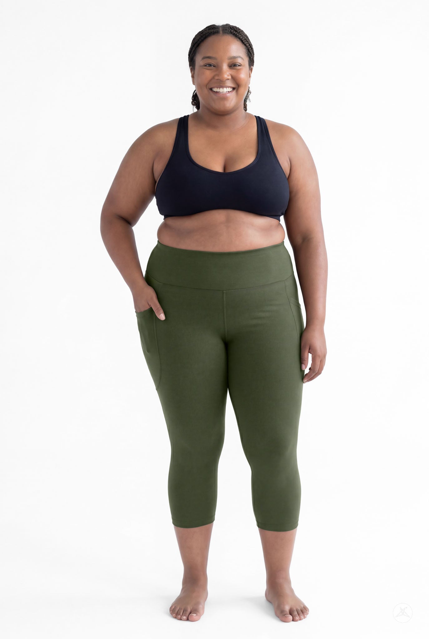 Plus size woman smiling barefoot wearing SweetLegs Cedar High-Waisted Pocket Crops in green with black sports bra