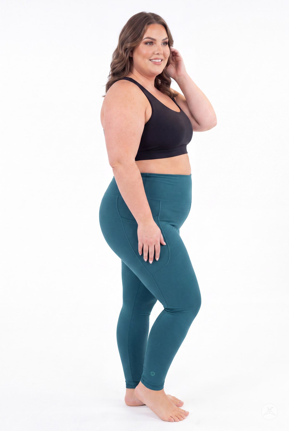 SweetLegs Deep Teal High-Waisted Pocket Leggings modeled in profile by a smiling woman in a black sports bra