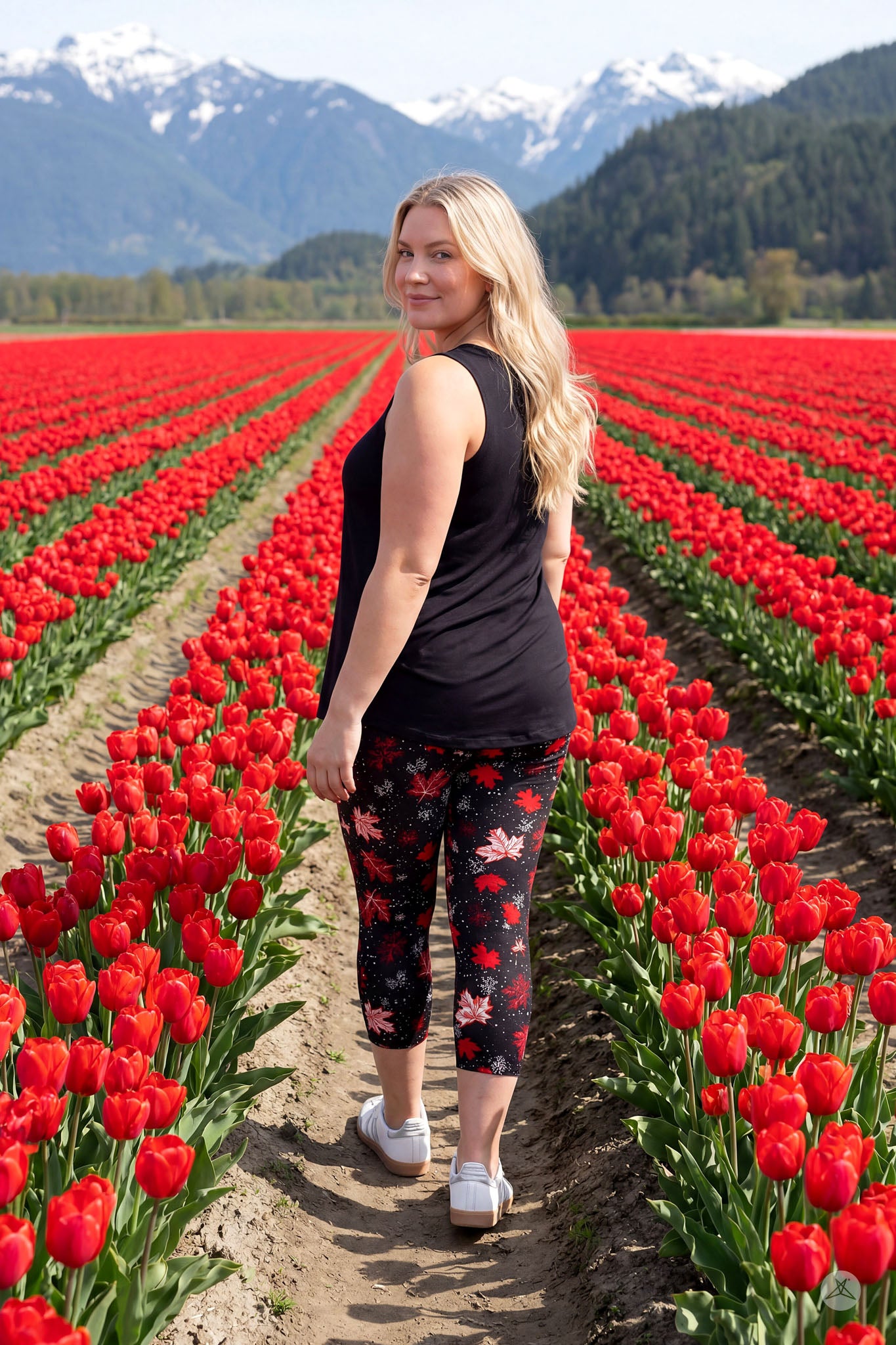 Woman walking through red tulip field wearing SweetLegs Maple Mood Crops with red and white leaf pattern and black sleeveless top
