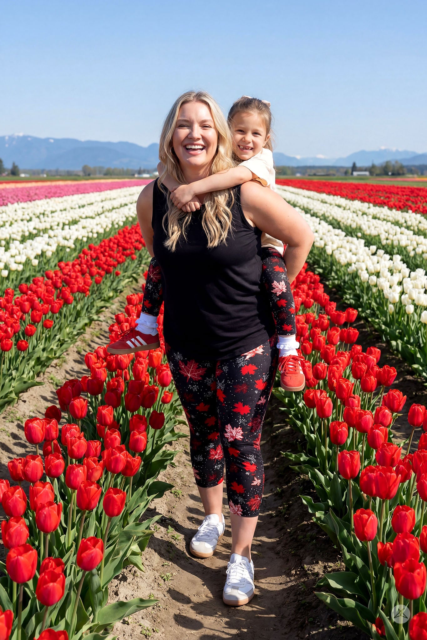 Woman and child wearing SweetLegs Maple Mood Kids leggings with red maple leaf pattern in tulip field outdoors