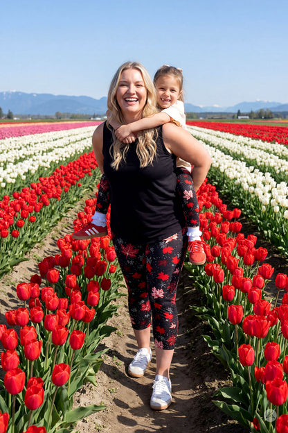 Woman and child wearing SweetLegs Maple Mood Kids leggings with red maple leaf pattern in tulip field outdoors