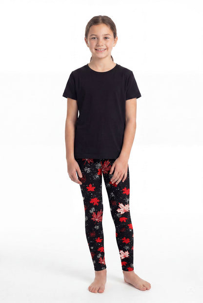 Girl wearing SweetLegs Maple Mood Kids leggings with red and white maple leaf pattern paired with black shirt barefoot