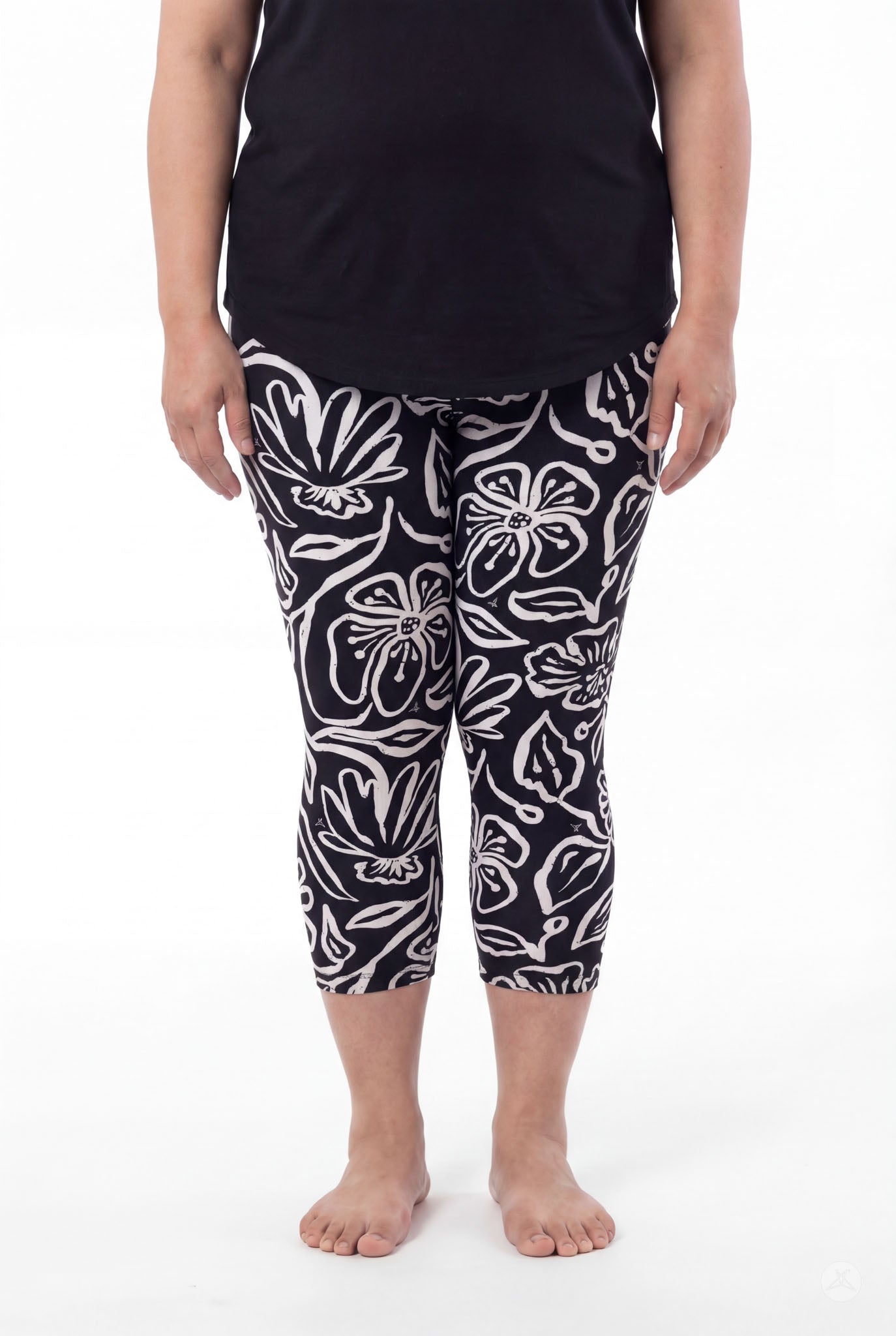 Plus size woman wearing SweetLegs Midnight Bloom Crops with bold black and white floral pattern paired with black top barefoot