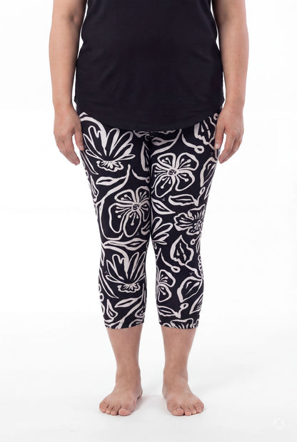 Plus size woman wearing SweetLegs Midnight Bloom Crops with bold black and white floral pattern paired with black top barefoot