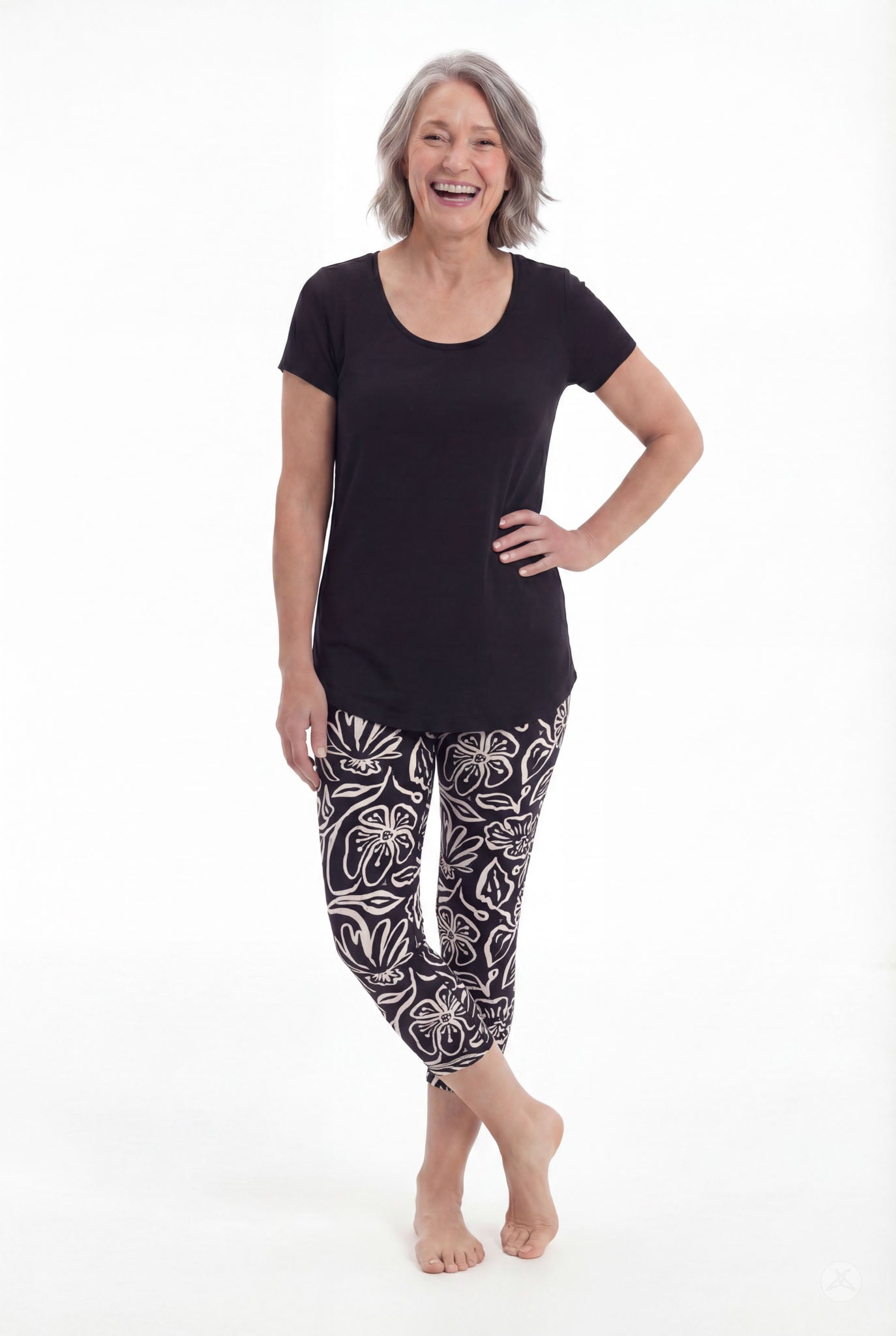 Woman smiling wearing SweetLegs Midnight Bloom Crops with bold black and white floral pattern and black top barefoot