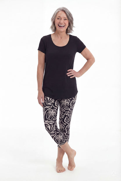 Woman smiling wearing SweetLegs Midnight Bloom Crops with bold black and white floral pattern and black top barefoot
