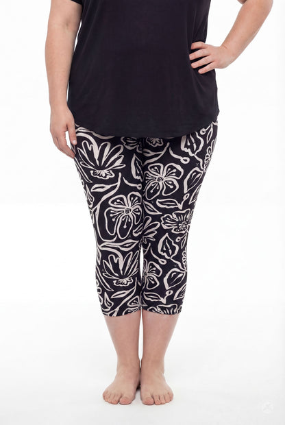 Plus size model wearing SweetLegs Midnight Bloom Crops with black and beige floral pattern and black top barefoot