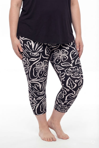 Plus size model wearing SweetLegs Midnight Bloom Crops with soft black and beige floral pattern paired with black top barefoot