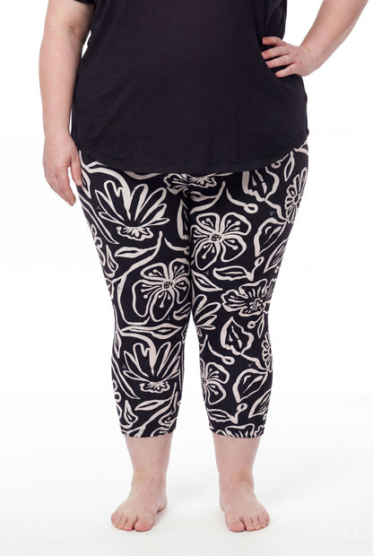 Plus size model wearing SweetLegs Midnight Bloom Crops in black and beige floral pattern paired with black top barefoot