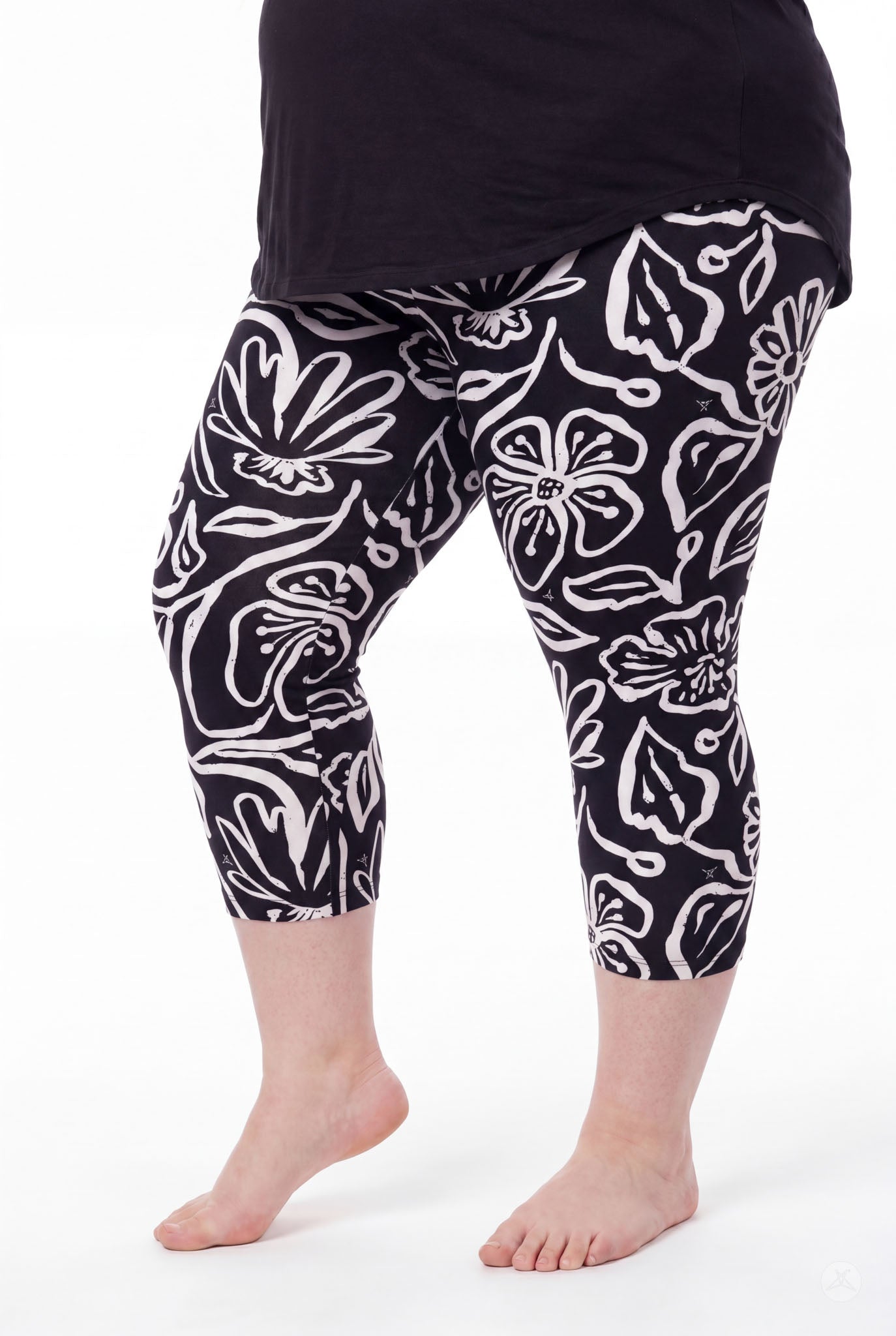 Plus size woman wearing SweetLegs Midnight Bloom Crops with bold black and white floral pattern barefoot standing side view