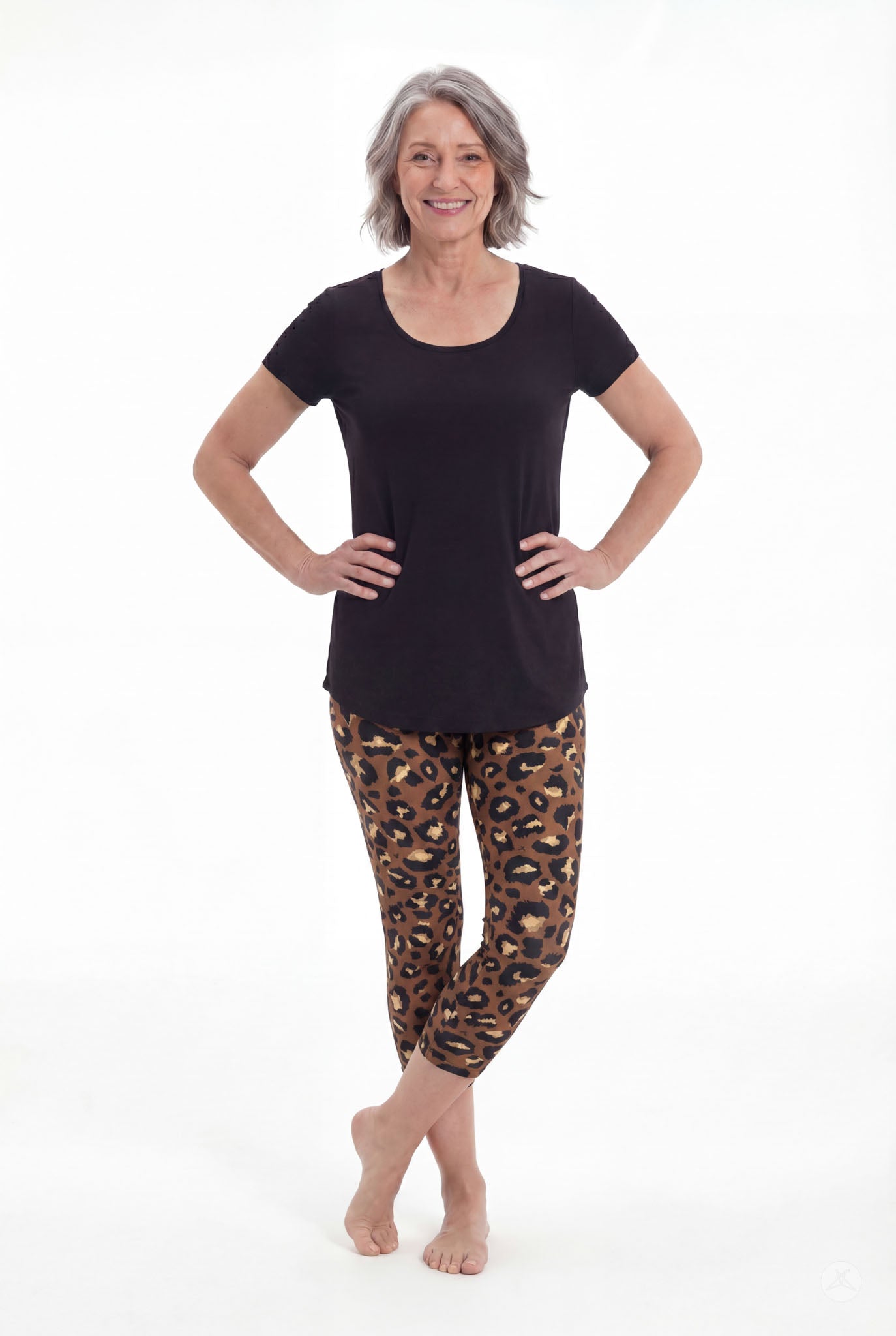 Smiling mature woman wearing SweetLegs Mocha Spots Crops with brown and black leopard pattern and a black tee barefoot
