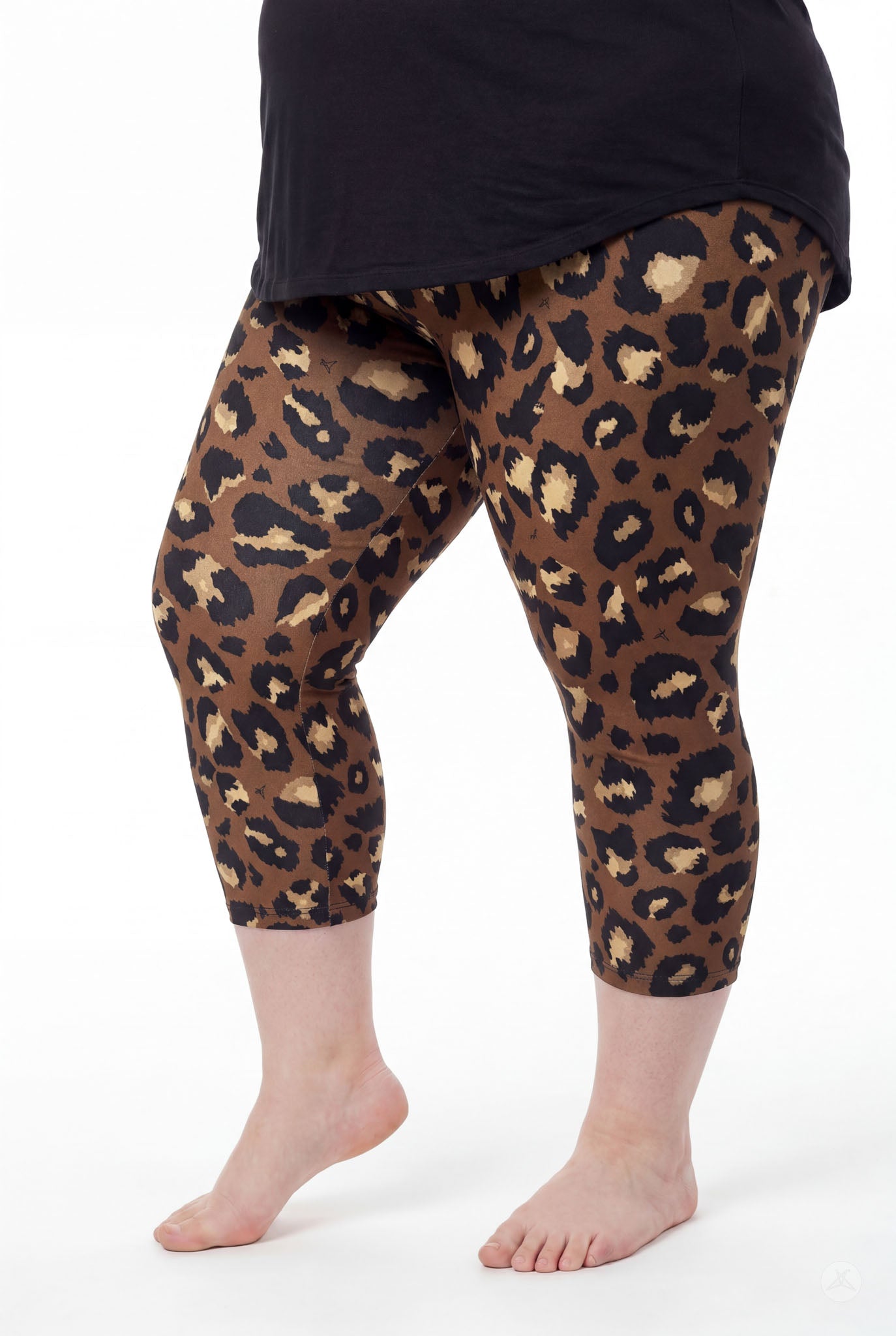 Curvy model wearing SweetLegs Mocha Spots Crops with bold brown leopard print and black top barefoot side view