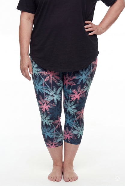 Front view of woman wearing SweetLegs Tiki Nights Crops with colorful palm tree pattern and black top barefoot