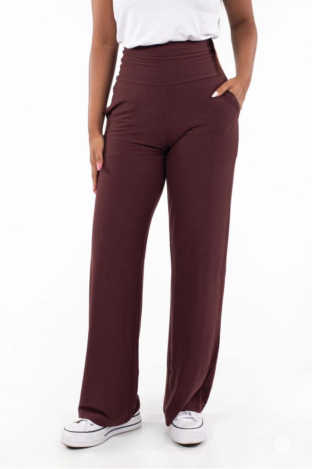 Woman wearing SweetLegs High-Waist Wide Leg Pants in brown with hand in pocket and white sneakers on white background