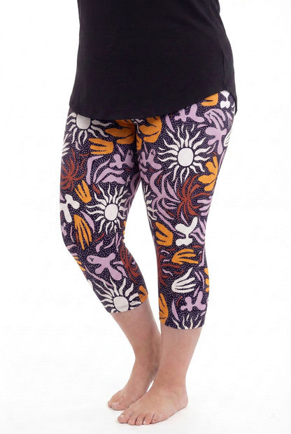Woman barefoot wearing SweetLegs Retro Petals Crops featuring colorful abstract floral and sun patterns with a black top