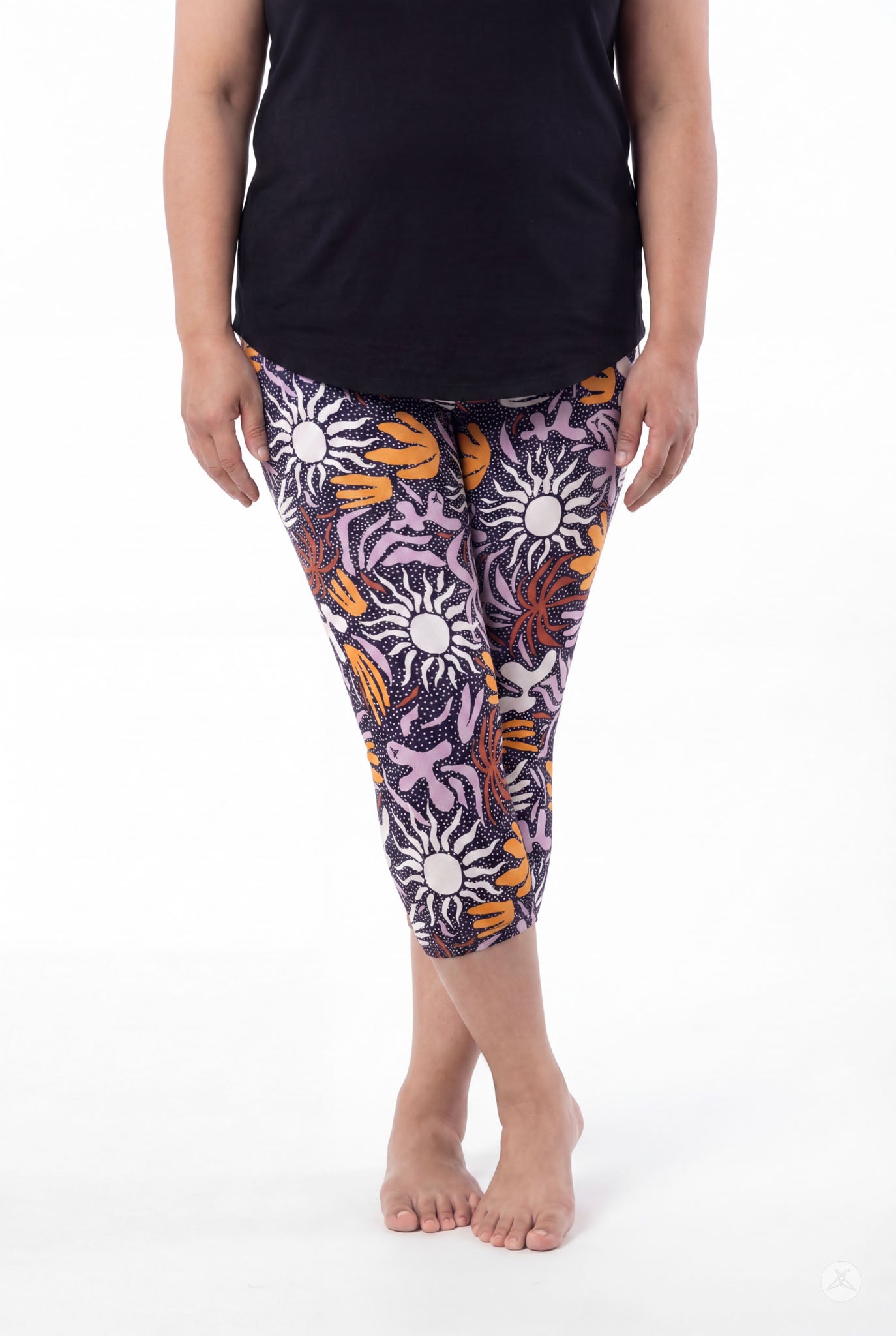 Woman wearing SweetLegs Retro Petals Crops with bold sun and abstract floral patterns in purple, orange, and white, barefoot