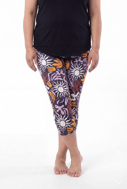 Woman wearing SweetLegs Retro Petals Crops with bold sun and abstract floral patterns in purple, orange, and white, barefoot