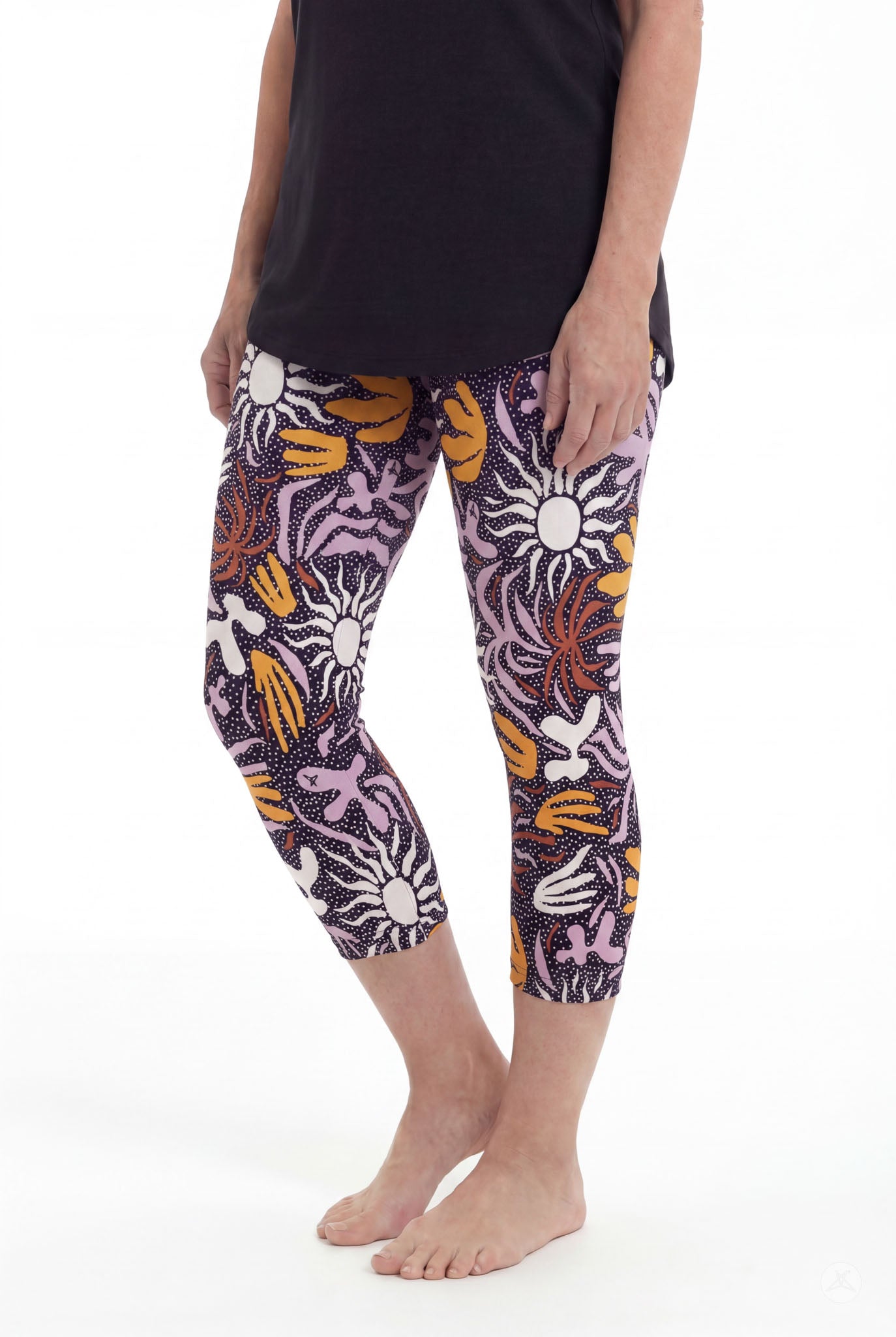 Woman wearing SweetLegs Retro Petals Crops featuring vibrant floral patterns in orange, white, and purple standing barefoot