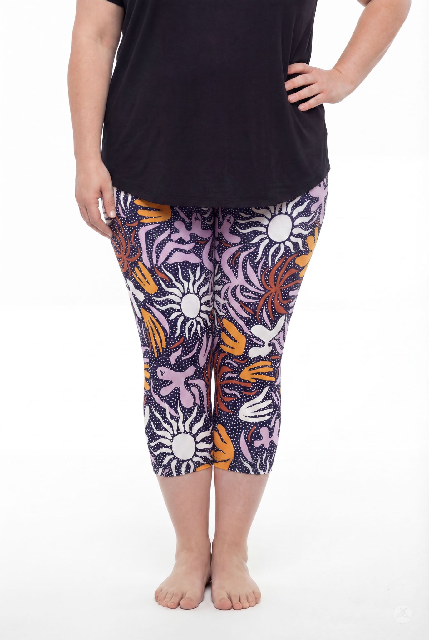 Curvy woman wearing SweetLegs Retro Petals Crops with colorful sun and abstract floral pattern and black top barefoot