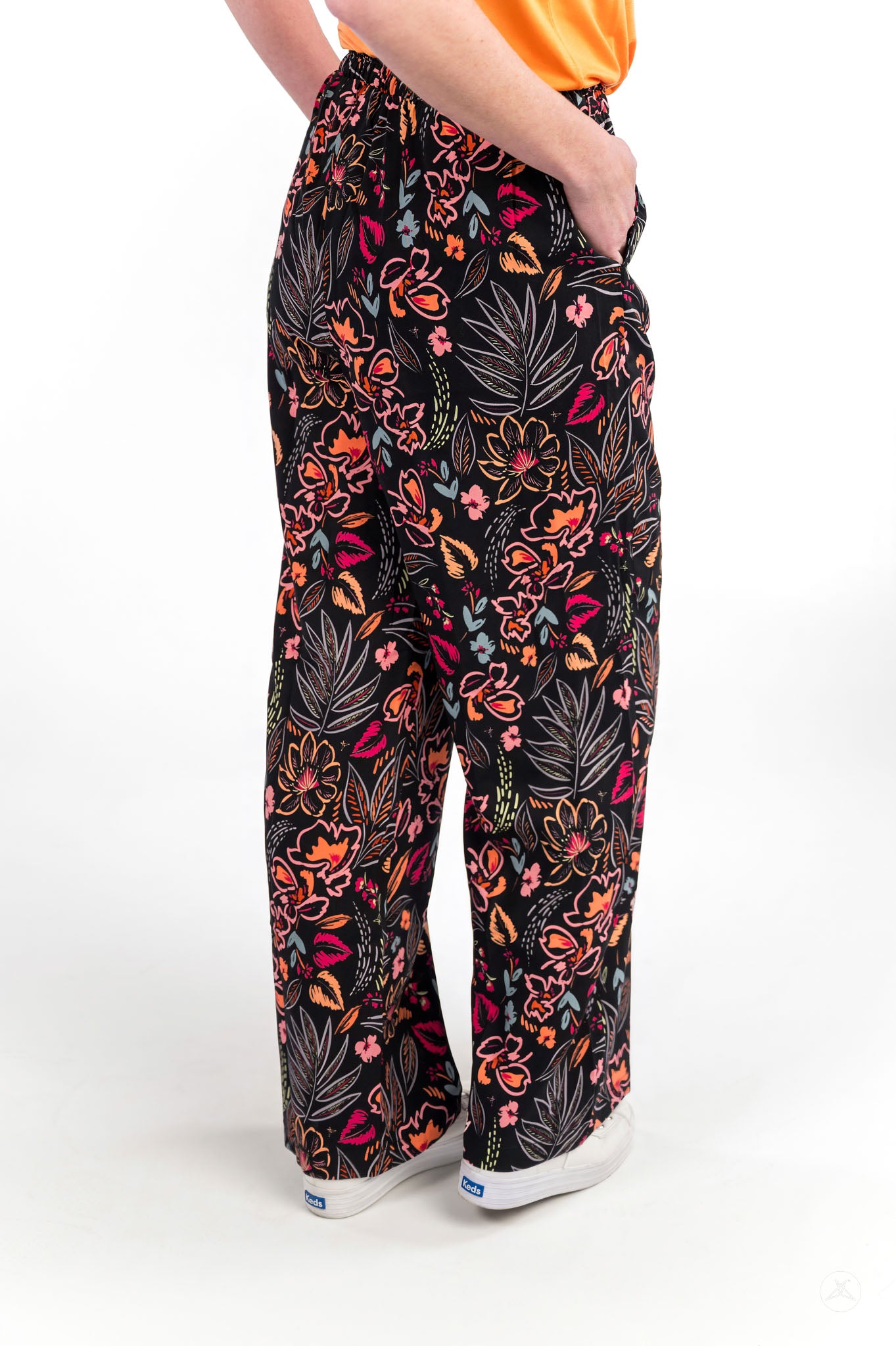 Person wearing sweetlegs Breeze Wide-Leg Pant in vibrant floral print with hands in pockets on white background