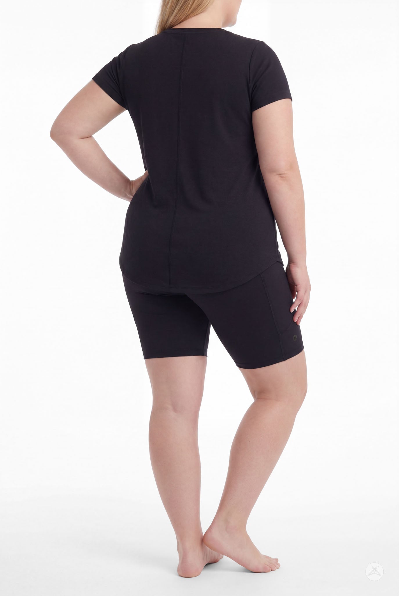 Plus size woman wearing SweetLegs Black Pocket Biker Shorts with black short sleeve top standing rear view barefoot