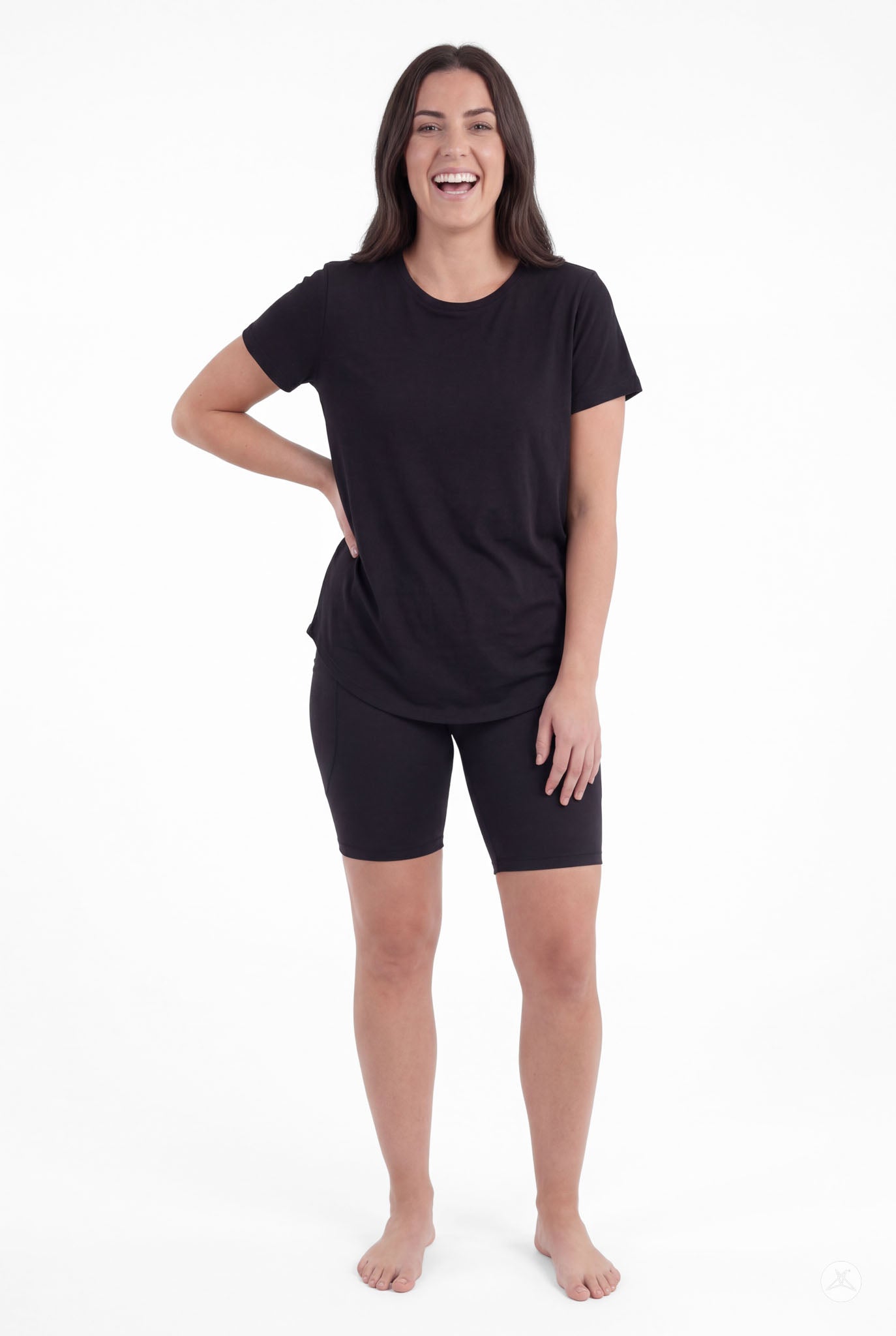 Smiling woman standing barefoot wearing SweetLegs Black Pocket Biker Shorts with black short sleeve top front view