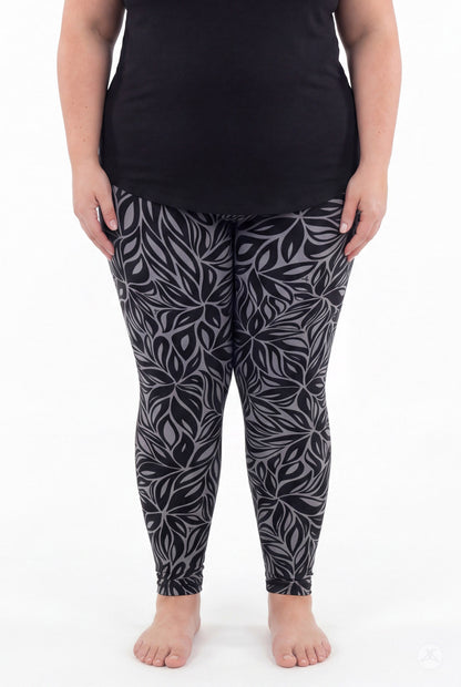 A model wears SweetLegs Shadow Petal Leggings in a dark gray botanical leaf print