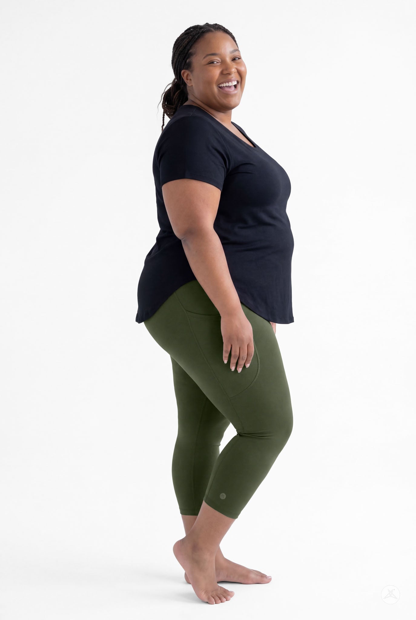 Plus size woman smiling wearing SweetLegs Cedar Pocket Crops in olive green with side pockets and black top