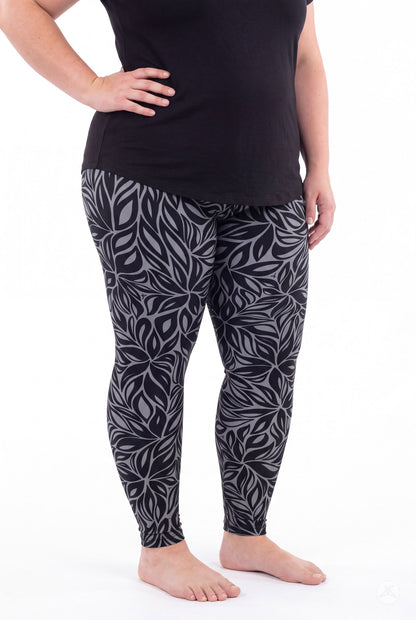 A model wears SweetLegs Shadow Petal Leggings in a dark gray leafy pattern