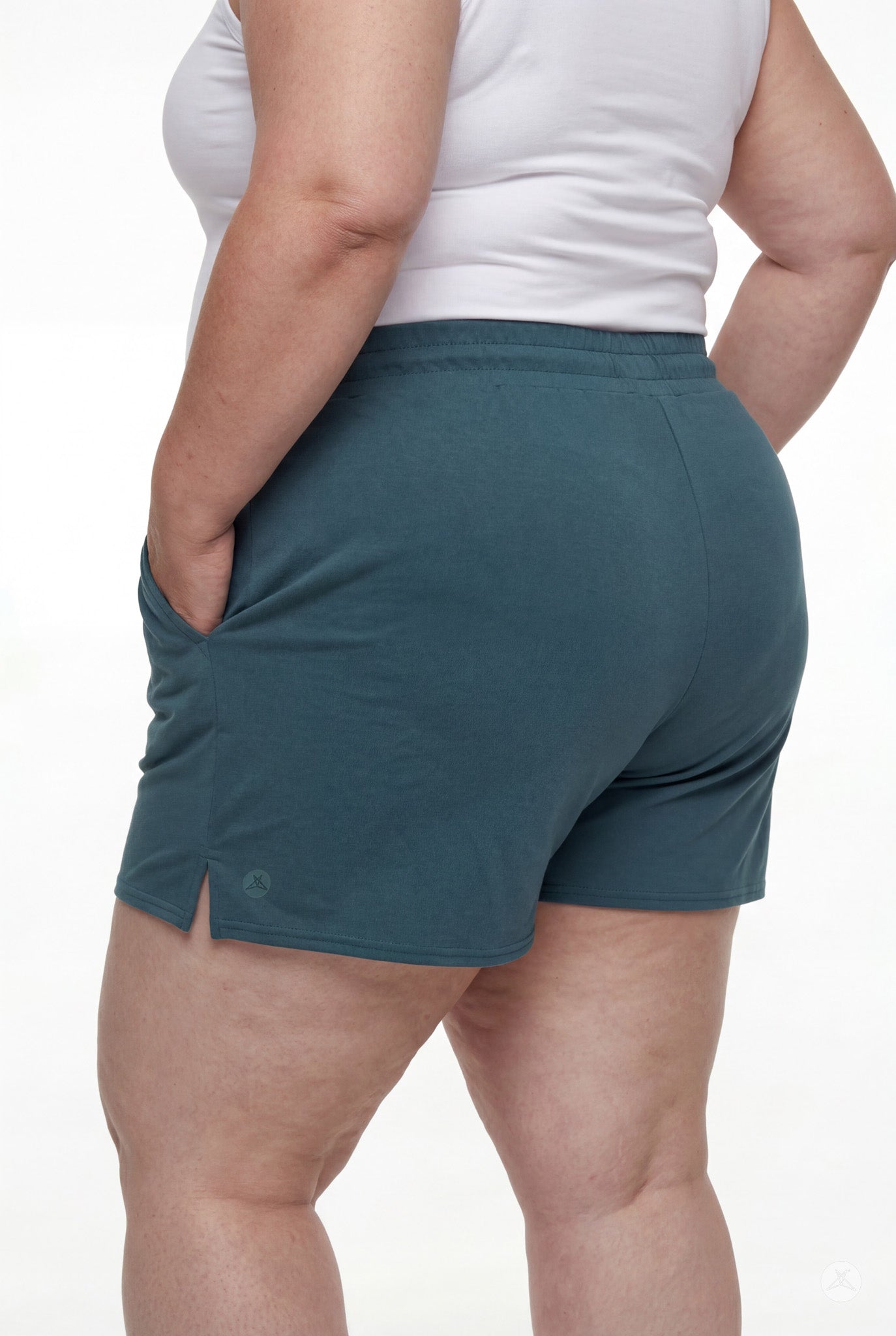 Rear view of person wearing teal Lounge Shorts by SweetLegs with elastic waistband, side slit, and hands in pockets