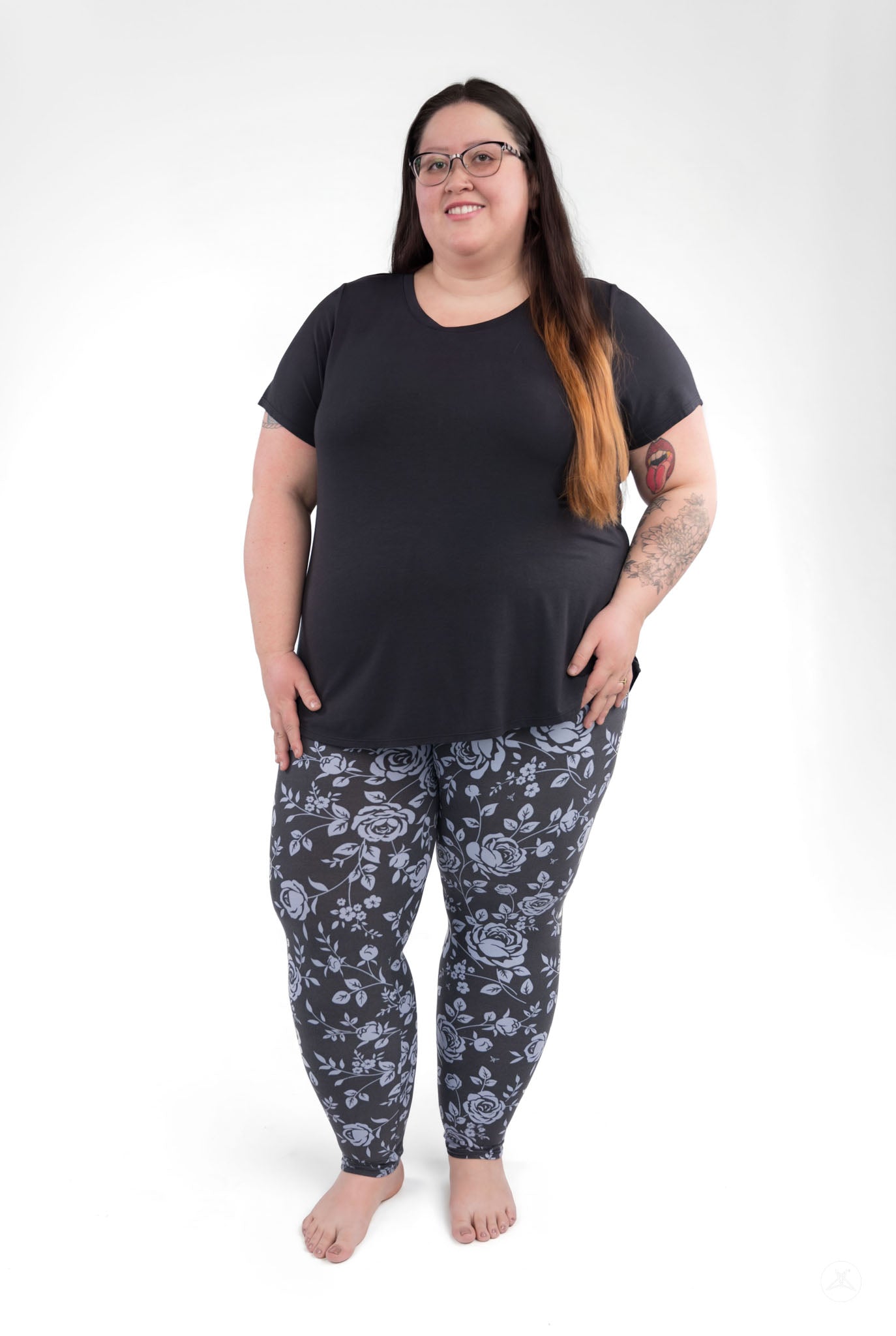 Plus size model wearing SweetLegs Shadow Garden leggings with grey-blue rose print on black background
